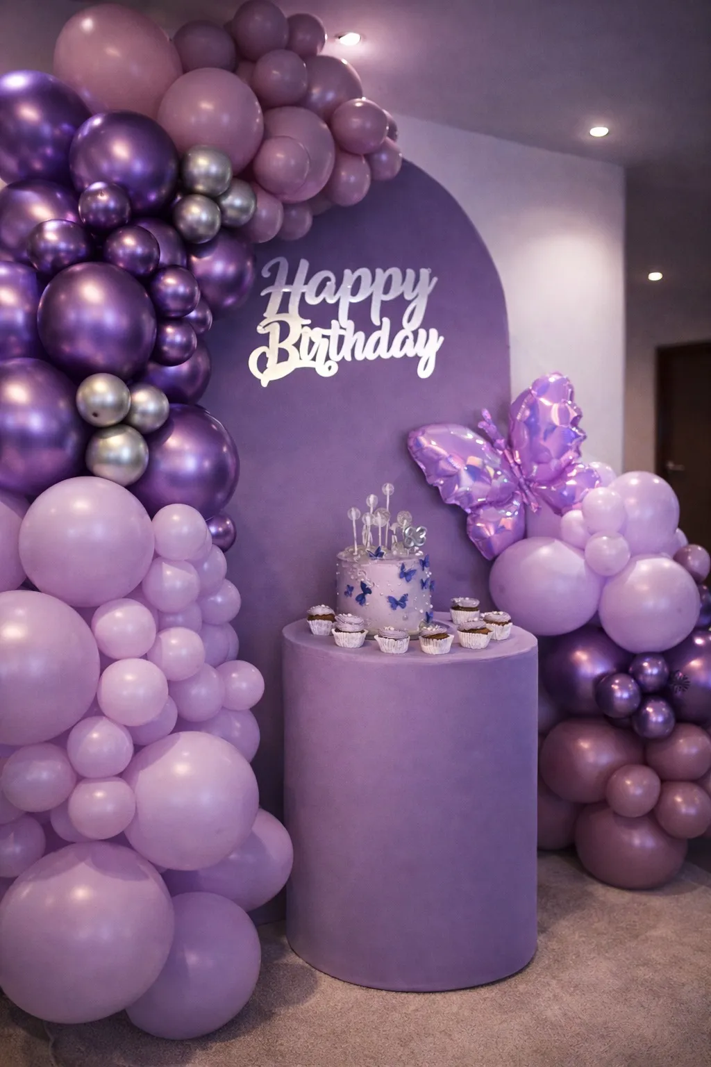 Montaje cumpleaños morado con globos cromados, mariposa y torta